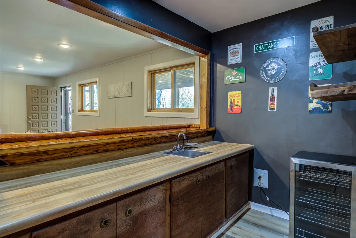 A warm, inviting bar area with a wooden counter, sink, and decorative wall signs, designed for entertaining and socializing with guests after a day outdoors. The relaxed atmosphere hints at gatherings and memorable evenings.