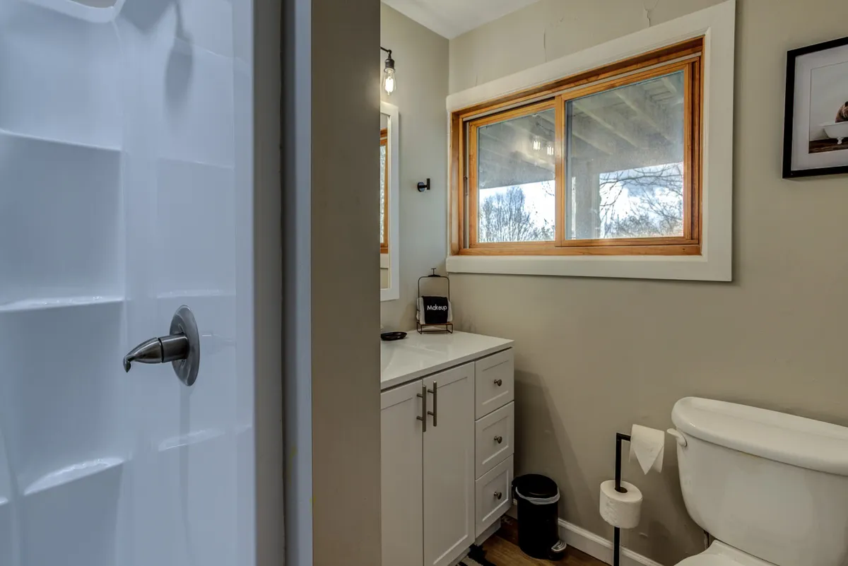 A bright and clean bathroom with a modern shower area, vanity with a sink, and a window allowing natural light. The serene setting is inviting for morning routines or relaxing after a long day.